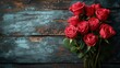 Bukiet czerwonych róż ustawiony na drewnianym stole. Leży płasko.