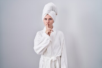 Canvas Print - Blonde caucasian woman wearing bathrobe asking to be quiet with finger on lips. silence and secret concept.