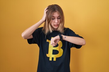 Wall Mural - Blonde caucasian woman wearing bitcoin t shirt looking at the watch time worried, afraid of getting late