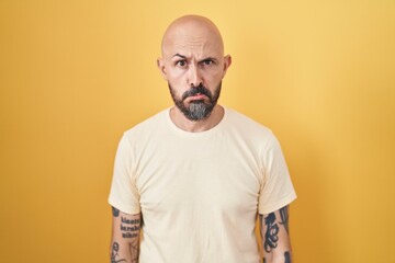 Poster - Hispanic man with tattoos standing over yellow background depressed and worry for distress, crying angry and afraid. sad expression.