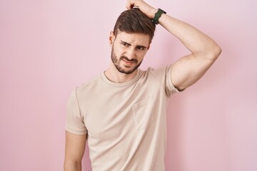 Poster - Hispanic man with beard standing over pink background confuse and wondering about question. uncertain with doubt, thinking with hand on head. pensive concept.