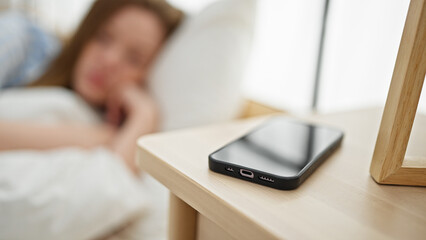 Canvas Print - Young blonde woman looking smartphone with sad expression at bedroom