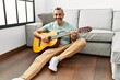 © Krakenimages.com - Middle age grey-haired man playing classical guitar sitting on floor at home