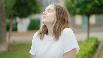 Wall Mural - Young caucasian woman breathing with closed eyes at park