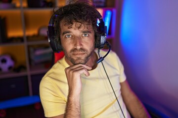 Canvas Print - Young hispanic man streamer sitting on table with serious expression at gaming room