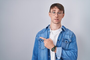 Poster - Caucasian blond man standing wearing glasses pointing aside worried and nervous with forefinger, concerned and surprised expression