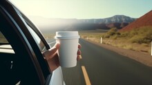An Outstretched Hand With A White Paper Coffee Cup Stretched Out Of The Window Of A Car Driving In Nature