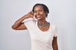 African woman with dreadlocks standing over white background smiling doing phone gesture with hand and fingers like talking on the telephone. communicating concepts.