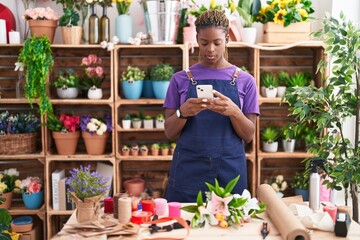 Wall Mural - African american woman florist using smartphone at florist