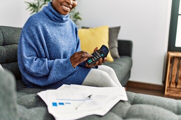 Canvas Print - African american woman using calculator accounting at home