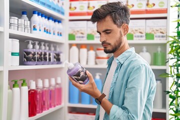 Wall Mural - Young hispanic man customer reading label gel hands bottle at pharmacy