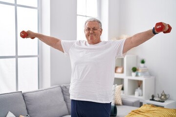 Wall Mural - Middle age grey-haired man smiling confident using dumbbells training at home