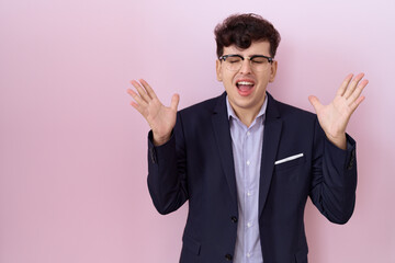 Wall Mural - Young non binary man with beard wearing suit and tie celebrating mad and crazy for success with arms raised and closed eyes screaming excited. winner concept