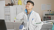 © Krakenimages.com - A young asian man in a white lab coat appears tired or stressed in a clinical laboratory setting.