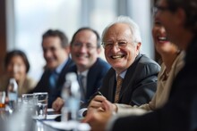 Senior Business People Sitting At A Table In A Conference Room And Laughing. A Lighter Moment During A Board Meeting, Where Executives Share Laughter And Camaraderie. 