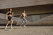 © Yaroslav Astakhov - Two young women in sportswear are running on modern buildings background. Active lifestyle concept