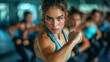 © summerhurricane - A young woman in a blue top displays fierce concentration and determination during a group exercise class