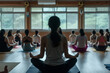 © MagnusCort - A woman in a gray tank top sits in a lotus position in a yoga class