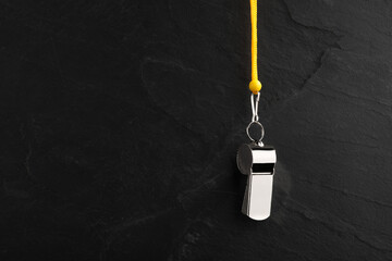 Wall Mural - Referee equipment. Metal whistle on black textured background, closeup and space for text