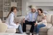 © fizkes - Young doctor visiting happy mature older couple of patients at home, talking to positive husband and wife, explaining prescription, telling good examination news, giving medical consultation