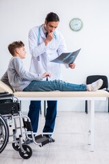 Wall Mural - Young male doctor pediatrist and boy in wheel-chair