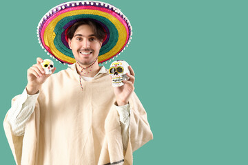 Canvas Print - Handsome young Mexican man with painted skulls on green background. Celebration of Day of the Dead