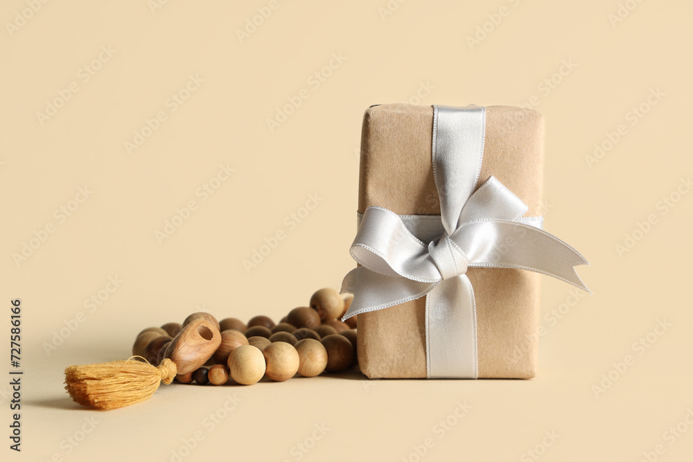 Gift box with prayer beads for Ramadan on beige background