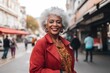 Attractive smiling white haired black mature woman posing in a city street looking at the camera