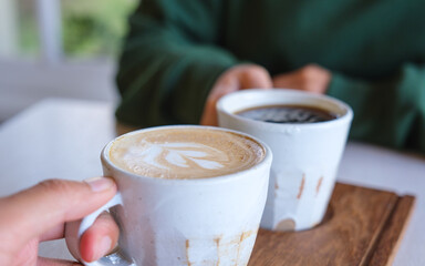 Wall Mural - Closeup image of a couple people holding and clinking coffee cups together in cafe