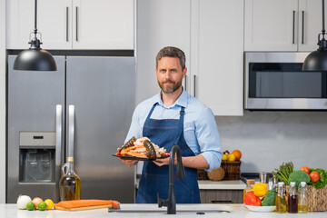 Wall Mural - Chef man in in cook apron cooking seafood in the kitchen. Restaurant menu concept. Cook in chef apron hold seafood. Portrait of chef man hold seafood in kitchen.