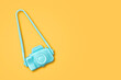 Small blue plastic camera, on a yellow background. Copy space. Travel concept. Photos of services. Background.