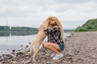© Smile - Young woman sitting with her labrador retriever dog on the river shore