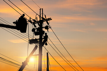 silhouette of electrician officer team climbs a pole and using a cable car to maintain a high voltag