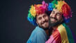 © Tepsarit - Cool looking gay couple wearing rainbow costume isolated on dark background withh copyspace for text. LGBTQ and pride month concept.