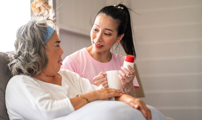 Portrait of love asian family senior mature mother and woman daughter care holding bottle tablet with pill and taking medicine with glass of water together.Healthcare senior people concept