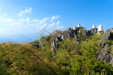 Lampang, Thailand : JANUARY 13,2024 : White of sky pagoda on mountain with blue sky. With green forest. Background at Wat Chaloem Phra Kiat Phrachomklao Rachanusorn Lampang Thailand.