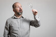 Surprised Caucasian man staring at empty wine glass, white background. Conceptual image of The Dry Challenge