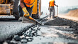 Road construction workers' teamwork, tarmac laying works at a road construction site, hot asphalt gravel leveled by workers, and road surface repair..