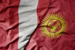 big waving national colorful flag of kyrgyzstan and national flag of peru .