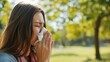 Woman with pollen allergy sneezes into handkerchief in a spring park