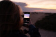 eine person fotografiert mit dem smartphone den sonnenaufgang in den dünen von corralejo auf fuerteventura auf den kanarischen inseln von spanien