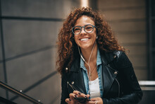 Laughing Young Woman With Glasses Listening To Music On A Metro Escalator