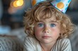 A young girl radiates joy and innocence as she dons a polka dot party hat, her piercing blue eyes captivating the viewer in this charming indoor portrait