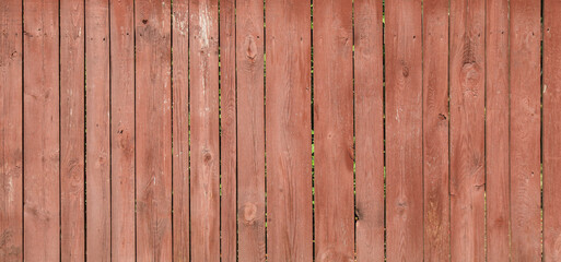  Red wooden surface, backdrop, background. Front view of an old wooden fence for inscription. Pink wood fencing. Surface, faded in the sun, shabby fence. Wooden fence boards with very faded pale paint