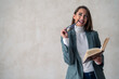 © Dorde - Smart female educator holding an open book for learning, studying and knowledge, isolated on a gray studio background.