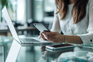 Poster - A woman sits at a desk using a laptop and a cell phone
