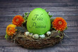 Felices Pascuas. Huevo de Pascua etiquetado con la inscripción Feliz Pascua en un nido con huevos de codorniz y flores.