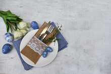 Easter Table Setting With Plates, Cutlery And Easter Decorations On A Gray Background. View From Above. Space For Text.