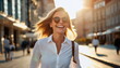 blonde woman in sunglasses and white shirt walks city street, smiling, laughing, enjoying outdoors on a sunny day