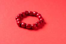 Handmade arm bracelet. Red bracelet on coral background